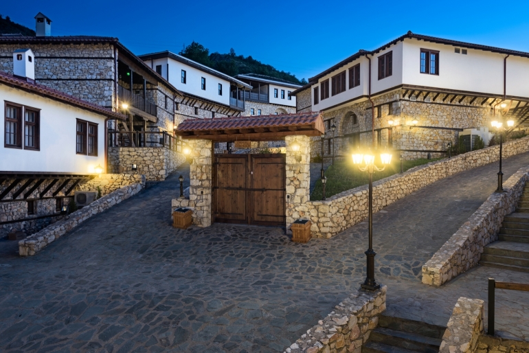 Tucked away on the slopes of Mount Vodno, just a short drive from the heart of Skopje, lies a attraction known as the Macedonian Village (Makedonsko Selo). This unique ethno-complex left a lasting mark on Macedonia’s tourism scene and remains a memorable part of the cultural heritage landscape. Its an immersive journey into the country’s traditional rural life, architecture, and folklore. Macedonian Village is created to showcase the authentic spirit of Macedonian culture and rural living. The complex features 16 beautifully constructed houses, each built in a traditional style specific to various regions across Macedonia. The village is designed like a real settlement, complete with cobblestone streets, wooden balconies, and charming gardens. Visitors can enjoy a peaceful walk among the houses, stop by small artisan workshops where craftspeople demonstrate traditional skills like pottery, weaving, and silverwork, or dine in the on-site restaurants that served homemade Macedonian cuisine. Dishes such as tavče gravče (baked beans), ajvar (pepper spread), and freshly baked bread give guests a taste of authentic Balkan and true Macedonian hospitality.